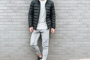 man in black jacket standing beside wall