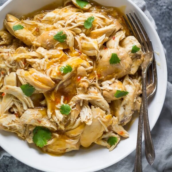 sweet chili chicken in white bowl with a fork and parsley sprinkled