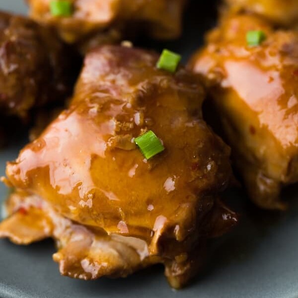 close up shot of sticky honey garlic chicken thighs on gray plate