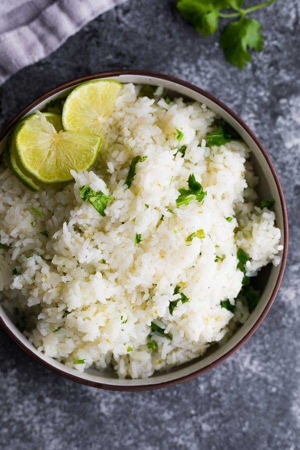 overhead shot of cilantro lime rice with lime wedge in brown bowl