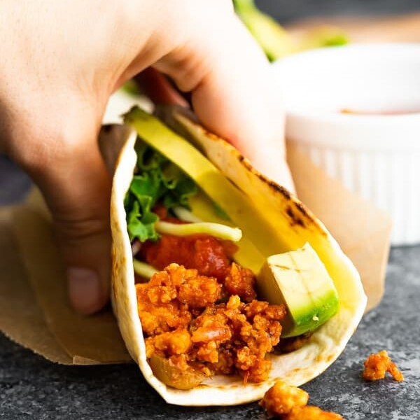 Close up of a hand holding a tofu taco