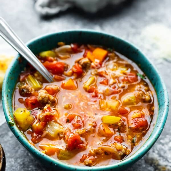 Italian sausage soup with farro in blue bowl  with a spoon