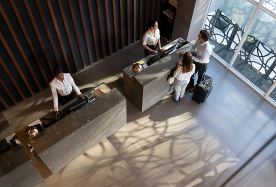 Overhead view of young business couple checking in at hotel and beautiful receptionist helping them very cheerfully