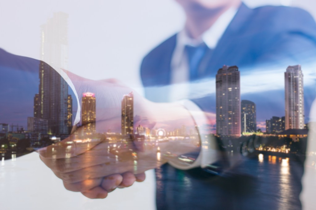 Double exposure concept. Investor business handshake with city night. Businessman shaking hands using as business partnership success concept, Teamwork concept, Investment, Growth