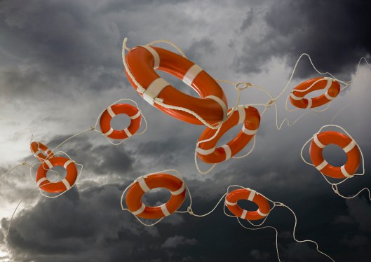 Life Rings flying out beneath storm clouds are a metaphor for rescue, help and aid.