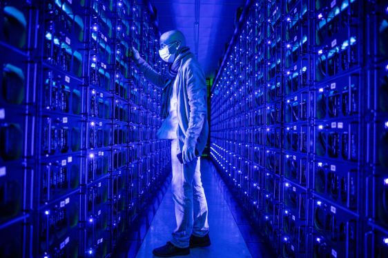 An employee wearing a protective face mask inspects mining rigs