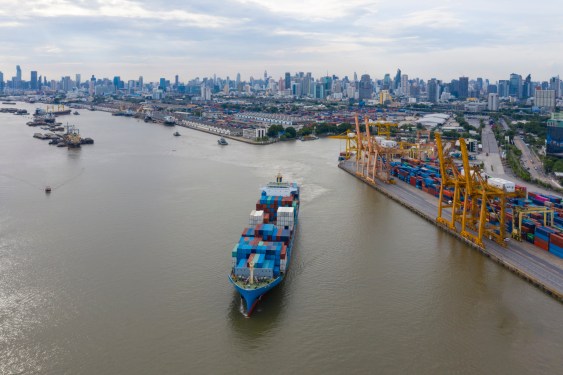 A photo of a container freight ship leaving a port in Thailand