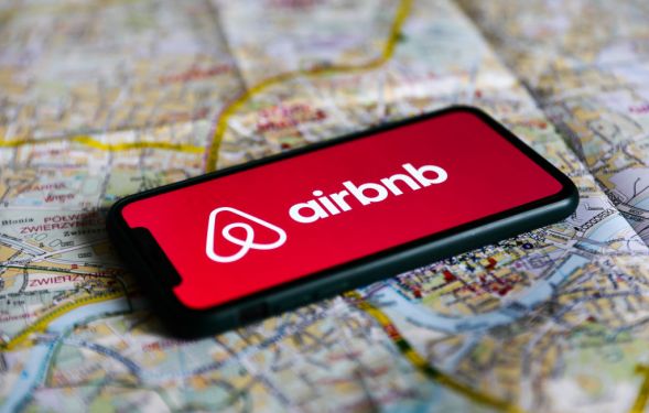 Airbnb logo displayed on a phone screen laying on a map of Krakow