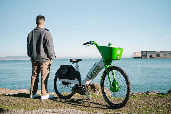 man looks out at san francisco bay standing next to lime e-bike