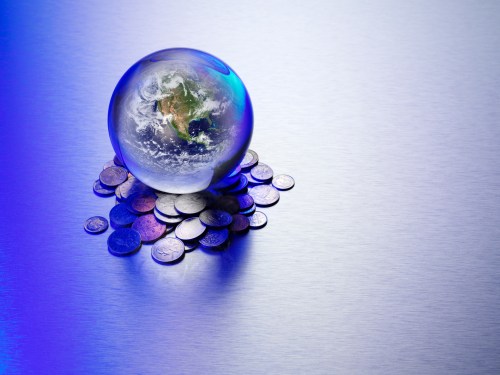 Image of a world map inside a crystal ball atop a pile of coins to represent predictions in venture capital for the year ahead.