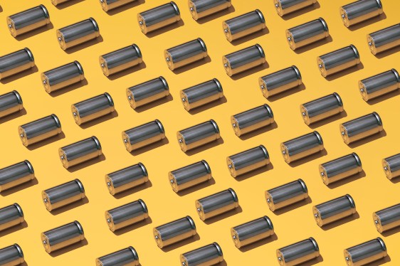 A large group of batteries laid in a pattern on a yellow background