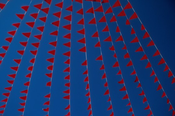 Image of red flags against a blue sky.