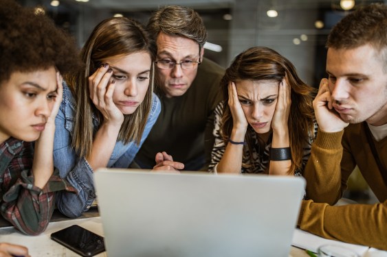 Team of unhappy designers gathered around a computer