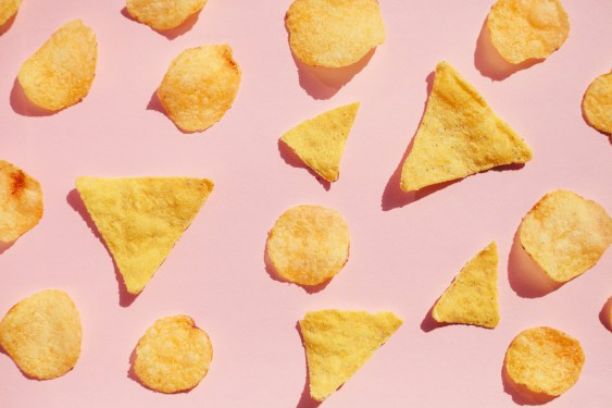 Potato chips pattern over pink background, hard light with shadows. Unhealthy junk food concept.