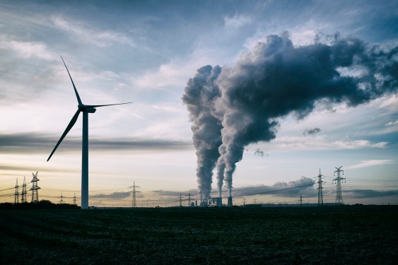 Wind turbine in the foreground of a coal-fired power plant.