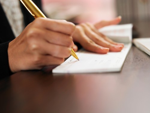 close up on hands writing a cheque