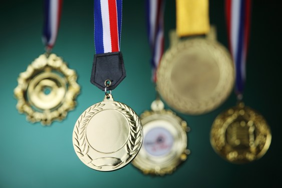 Close-Up Of Gold Medals Against Blackboard