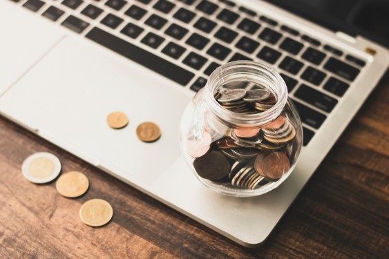 save and finance concept, money coin in jar with laptop on table