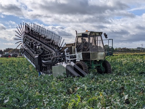 Agtech startup Upp's broccoli harvester shown attached to a tractor in a crop field