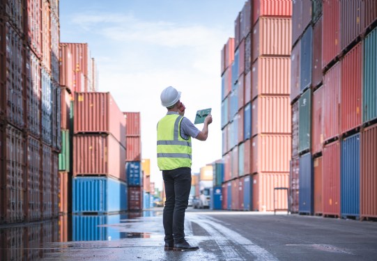 Engineer and tablet at Containers yard from Cargo freight ship for import export, used in a post about Freightify