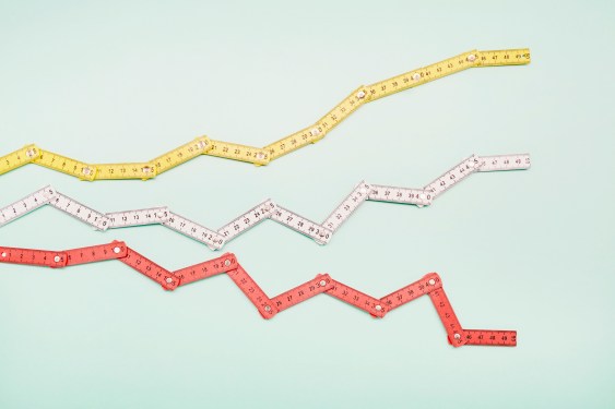 High angle view of folding rulers in shape of a stock curve on turquoise background