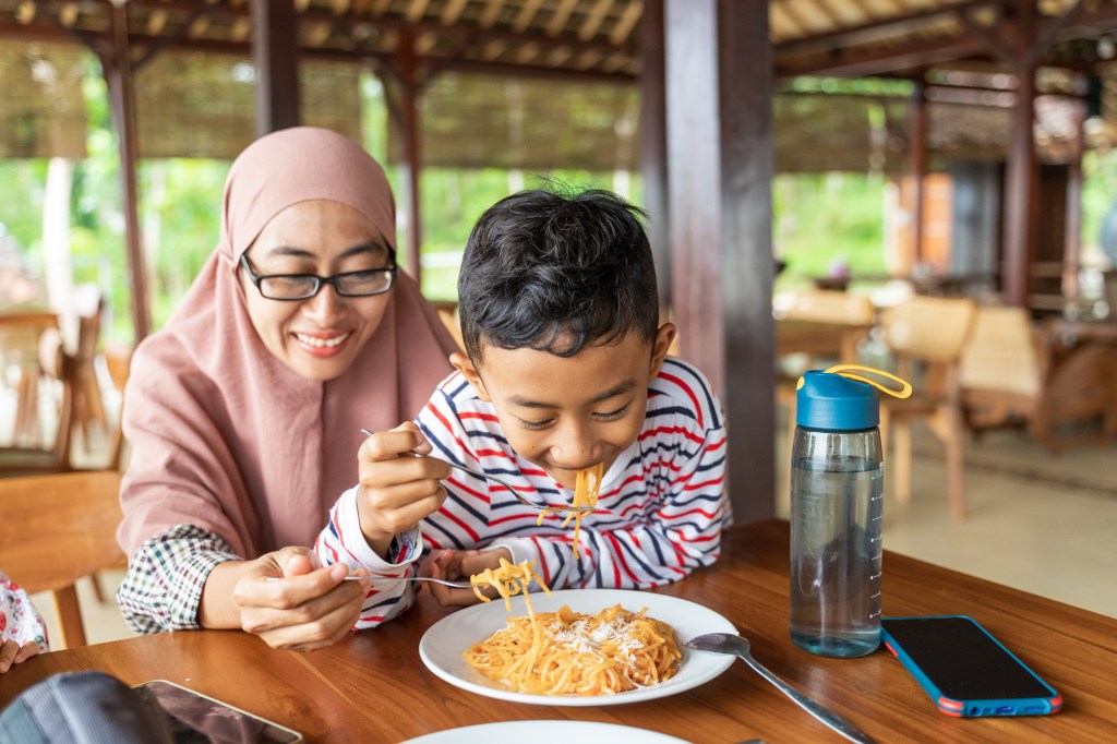 Asian young mother eating and feeding her son, used in a post about Legit Group