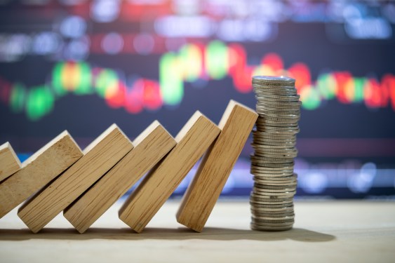 wooden blocks fall domino-style into stack of coins