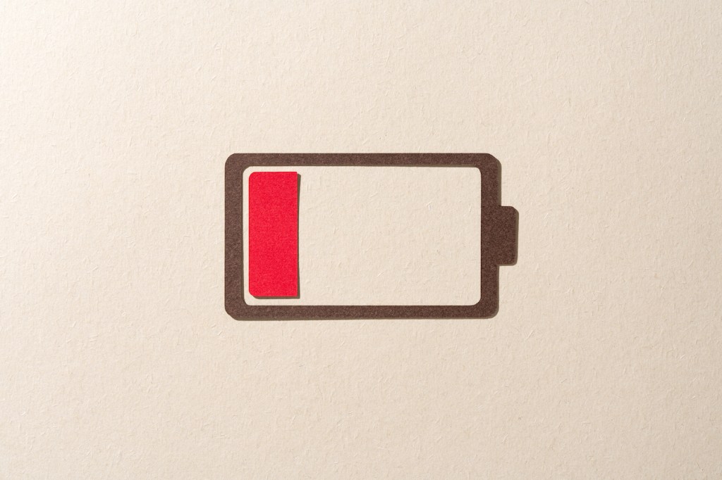 Paper Cut Craft Battery Only Has One Red Cell Left on Beige Background Directly Above View.