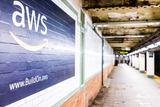 White AWS logo on blue tile background in subway in NYC.