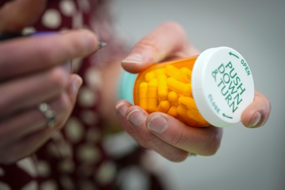 a pair of hands writing on a prescription label of a pill bottle in a pharmacy