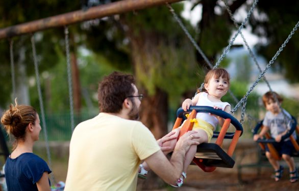 A man pushes his child in a swing.