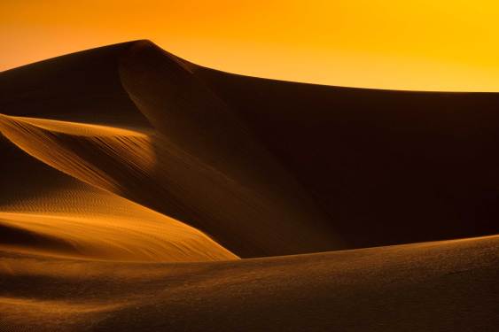 Tall sand dunes loom at sunset in California near the border with Mexico.