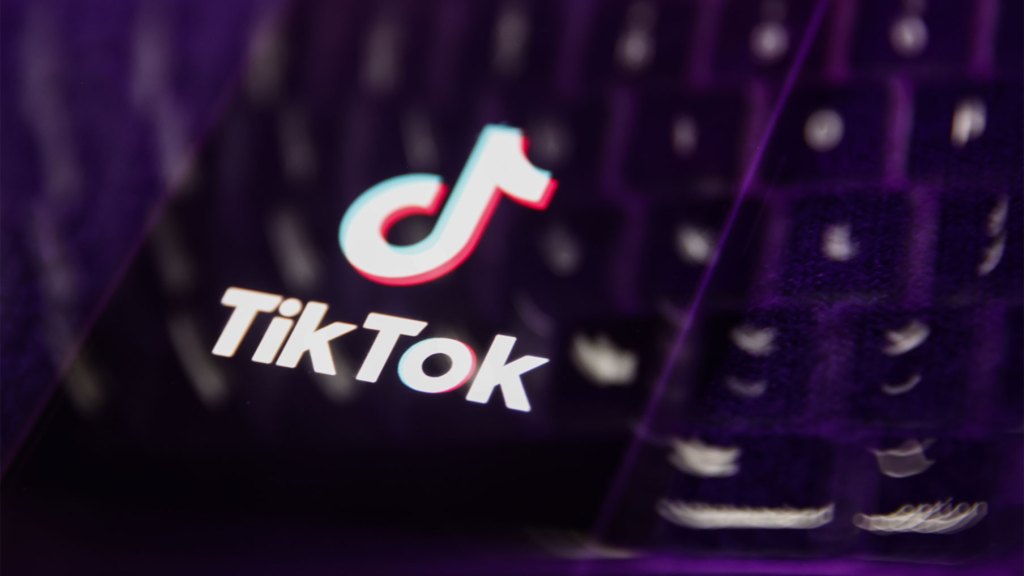 A laptop keyboard and TikTok logo displayed on a phone screen are seen in this multiple exposure illustration.
