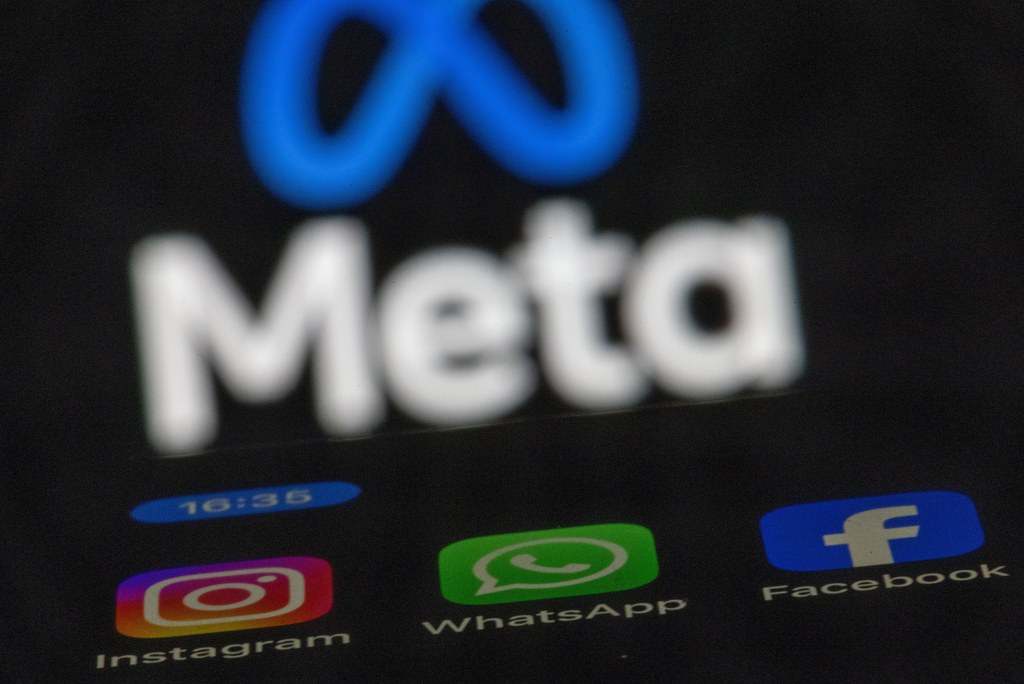 The apps Instagram, Facebook and WhatsApp can be seen on the display of a smartphone in front of the logo of the Meta internet company.