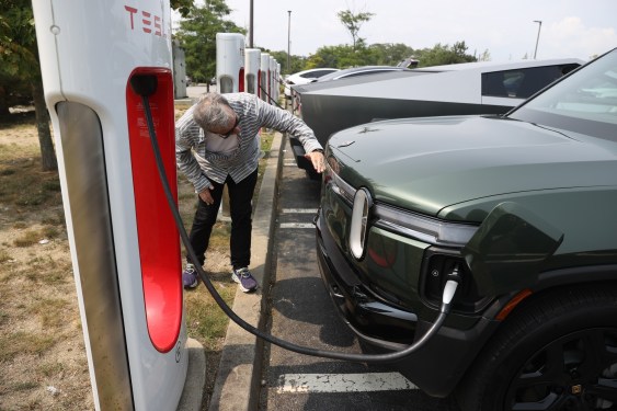 Rivian SUV charging at a Tesla Supercharger.