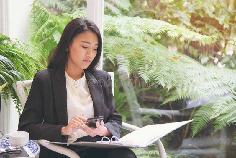 Elegant young business woman looking at document summary and using smartphone for calculator business income stock image