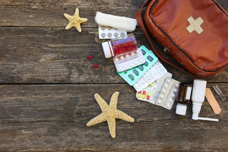 First aid kit on old wooden background. Concept of medication required in journey. Top view. Flat lay