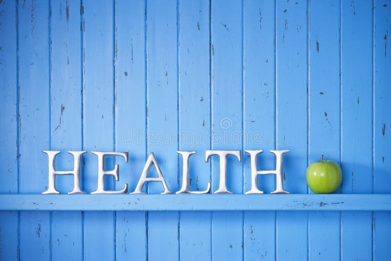 A blue painted wood background with the word health on it with a green apple. A blue painted wood background with the word health on it with a green apple