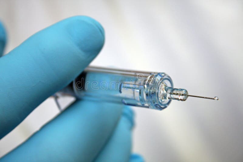 Injection needle held by gloved hand stock images
