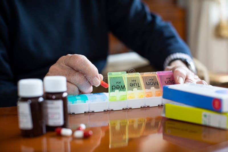 Close Up Of Senior Man Organizing Medication Into Pill Dispenser