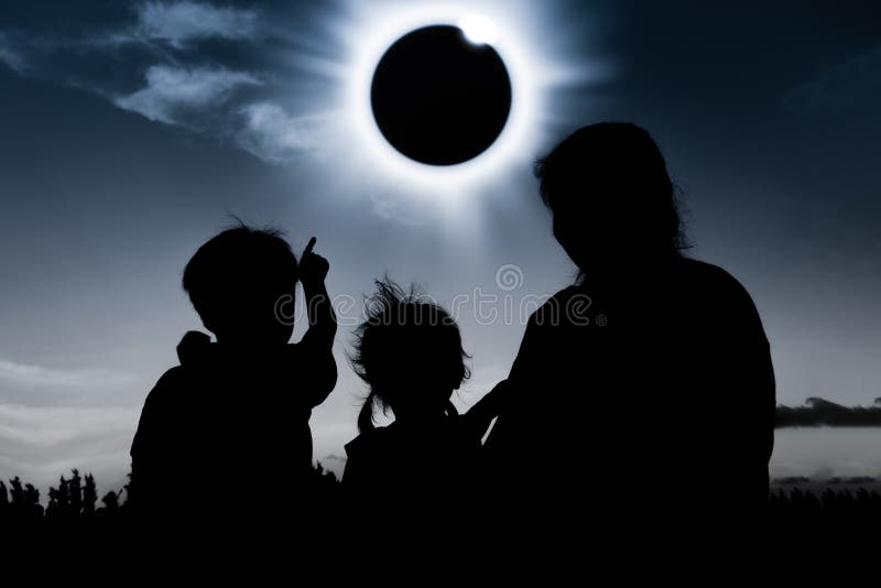 Silhouette back view of family looking at solar eclipse on dark