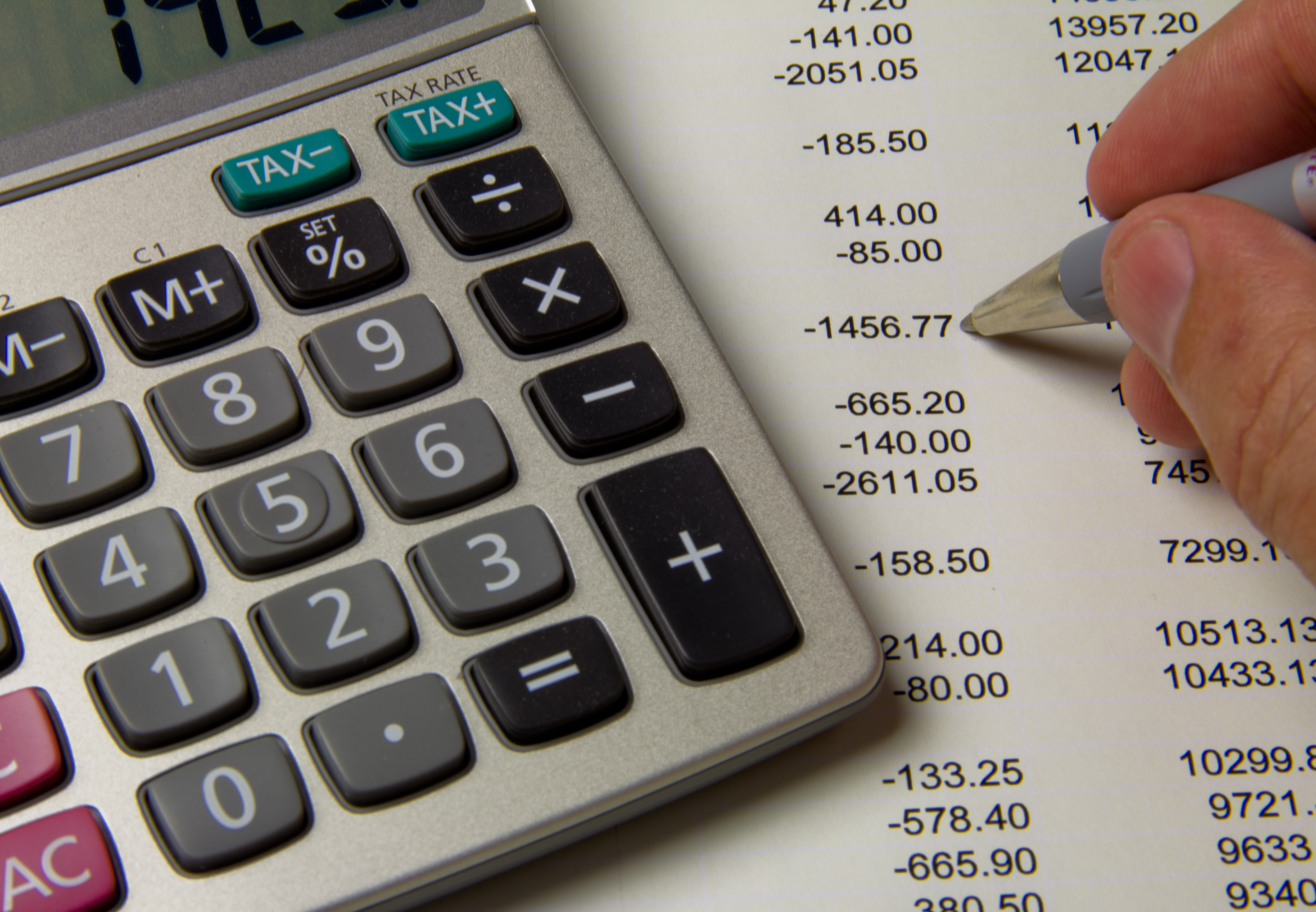 Close-up of someone doing their accounts with a pen and a calculator