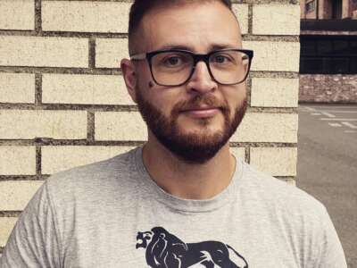 a photo of shane burley a white man with glasses and brown hair and cleanly shaven beard.