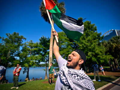 A protester chants while holding aloft the Palestinian flag