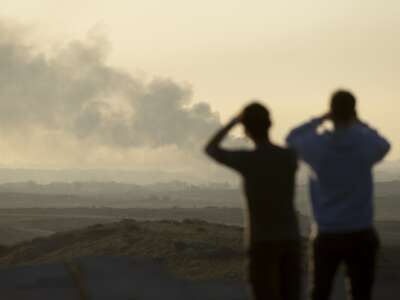 People look at smoke rising over the Gaza Strip as they are standing in a view point in the Israeli southern city on January 13, 2025 in Sderot, Israel.