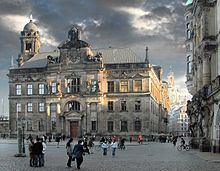 Barevná fotografie s pohledem na vrcholně barokní palác s průčelím a věží, za nímž je vidět kostel Frauenkirche