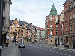 Barevná fotografie zobrazující pohled na bloky obytných domů a nárožní dům s věžičkou