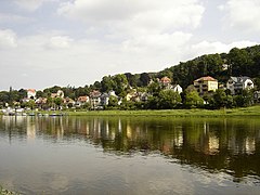 Barevná fotografie zachycující klidnou hladinu Labe a z části zalesněný břeh s několika domy