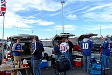 Fans in jerseys standing behind open SUVs