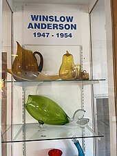 display of products by Winslow Anderson including gold colored wares and a green fish vase